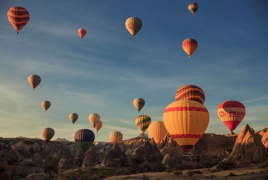 Hot air balloons rising over the fairy chimney rock formations of Cappadocia in Turkey at sunrise
