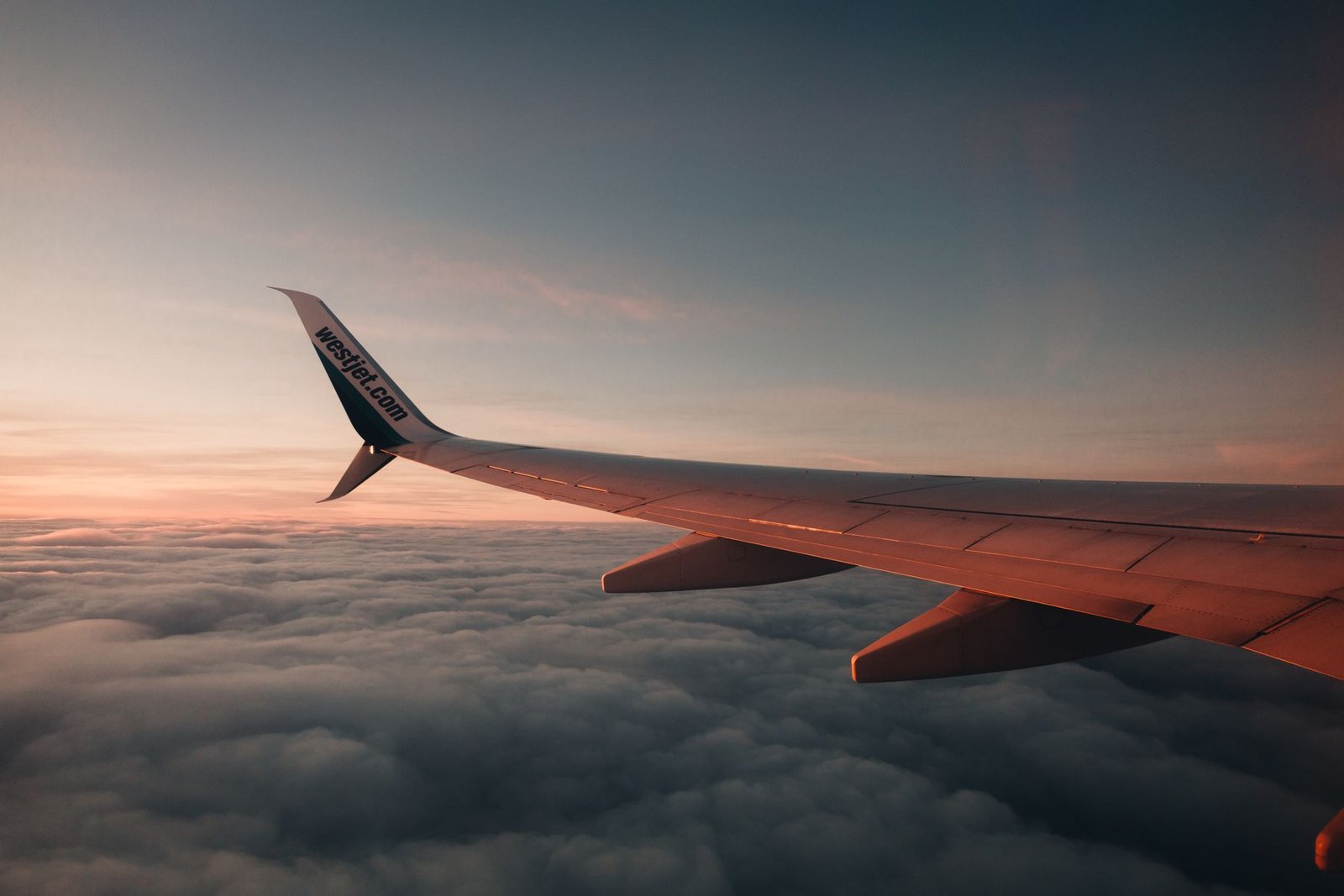 Aircraft wing above a golden cloud layer at sunset on an international flight departing Pakistan