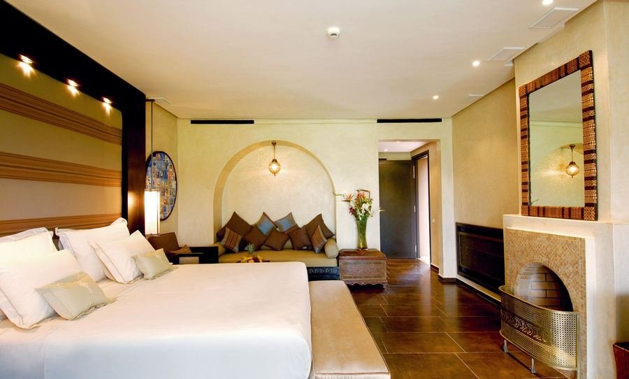 Warmly lit luxury hotel suite with a king bed, arched alcove seating and brass lantern lighting